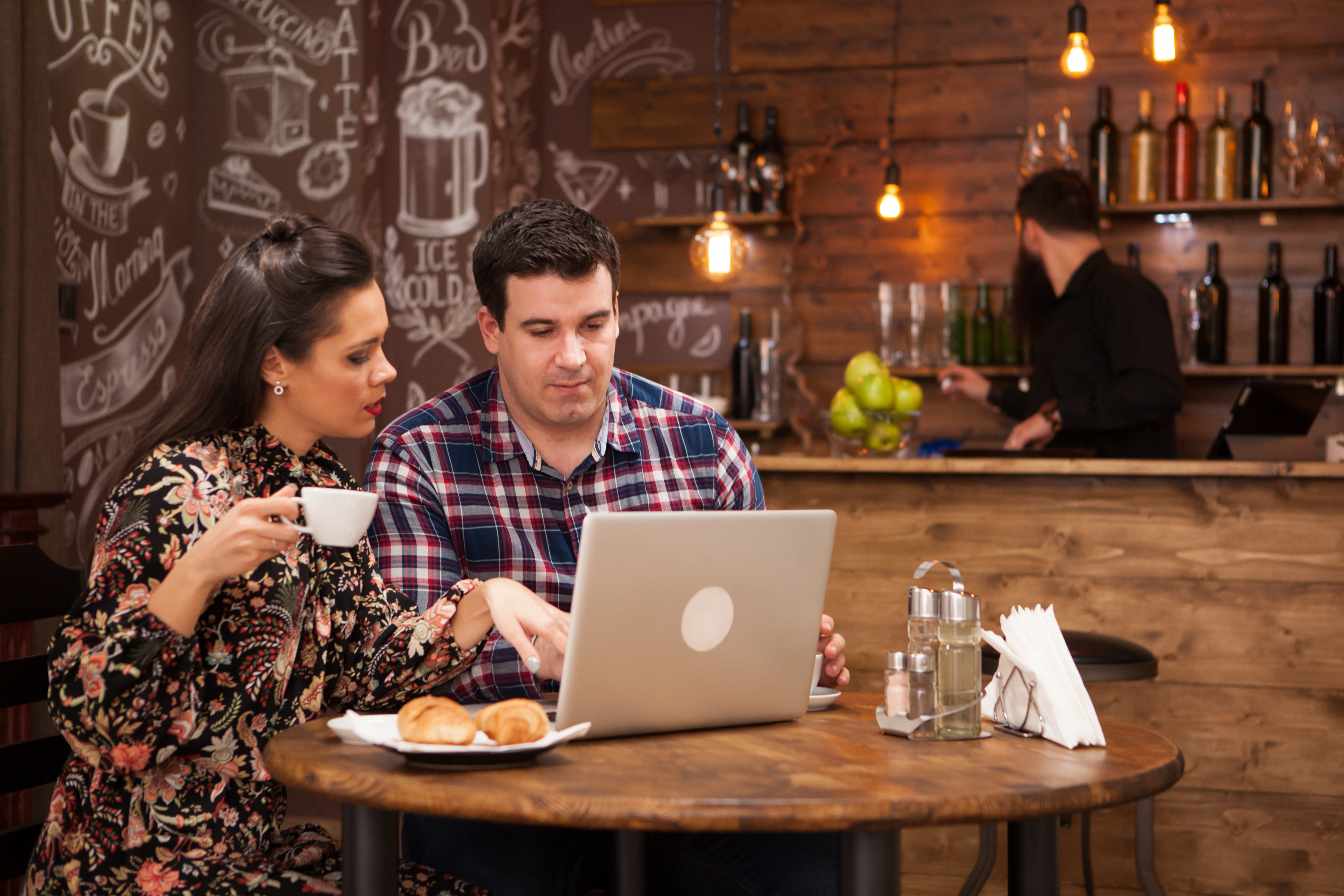 Man and woman at table in a restaurant looking at a laptop. Image by Freepik.