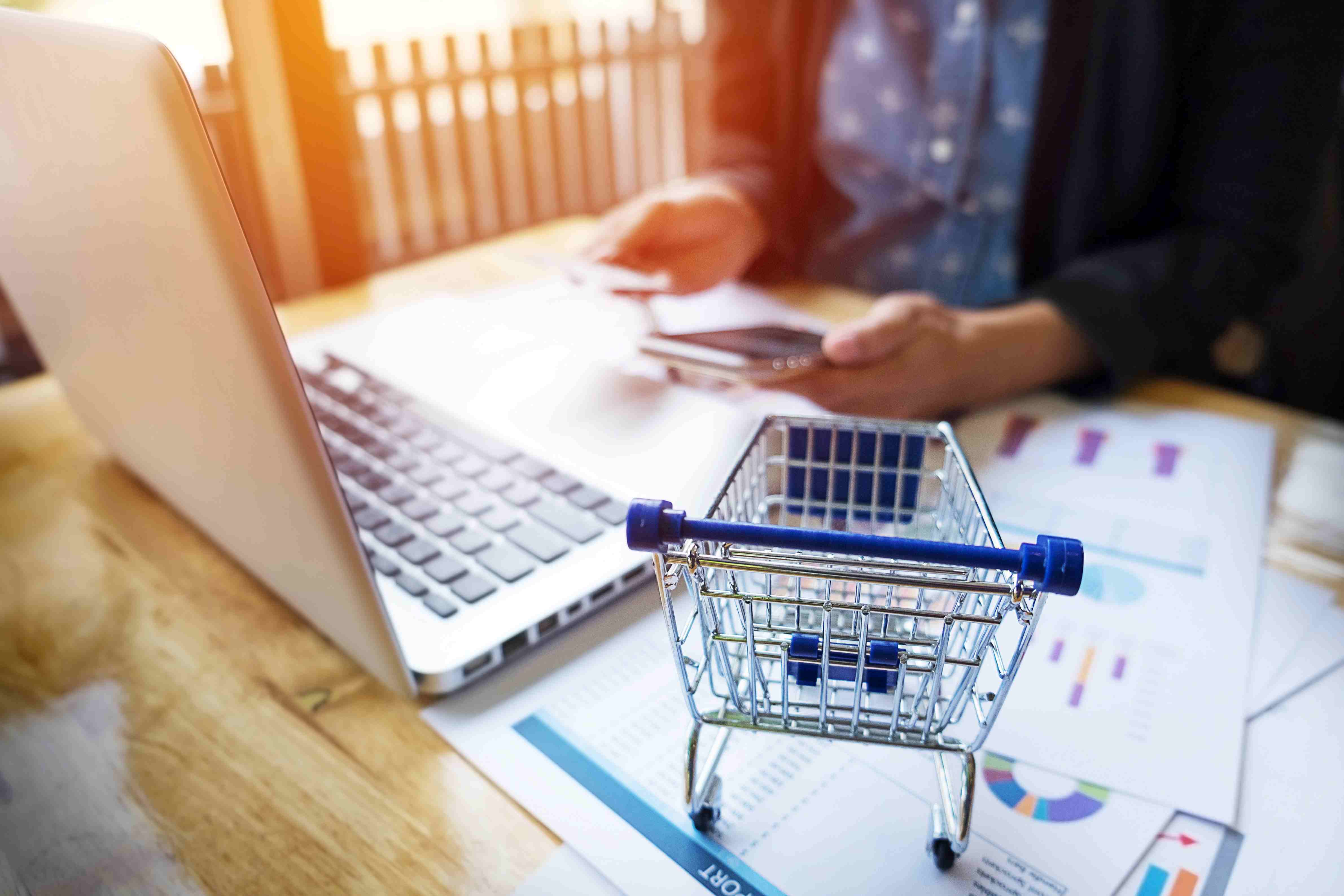 Person at computer with a shopping cart, image by Freepiks.