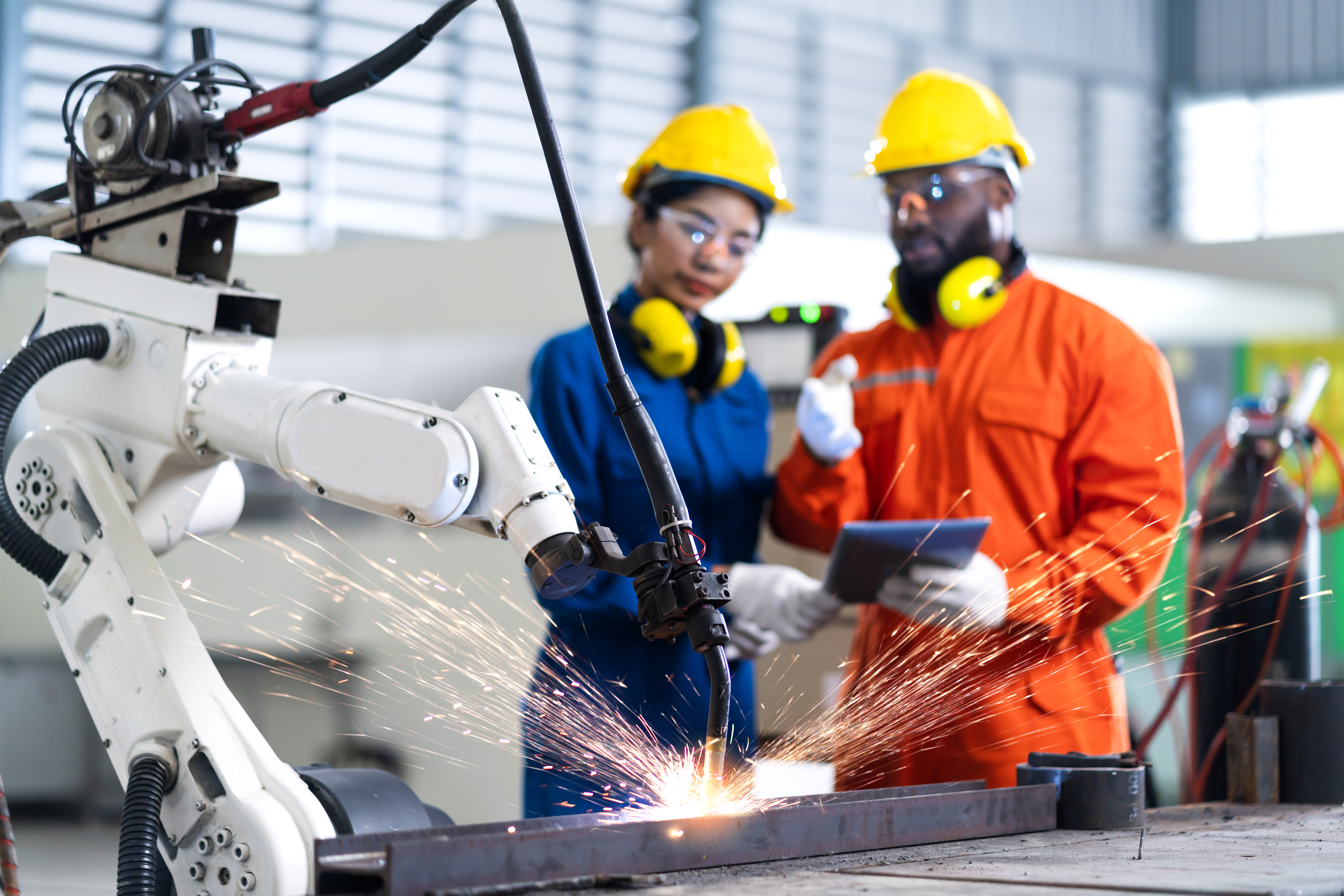 Two manufacturing experts watching robotic welding on assembly line.