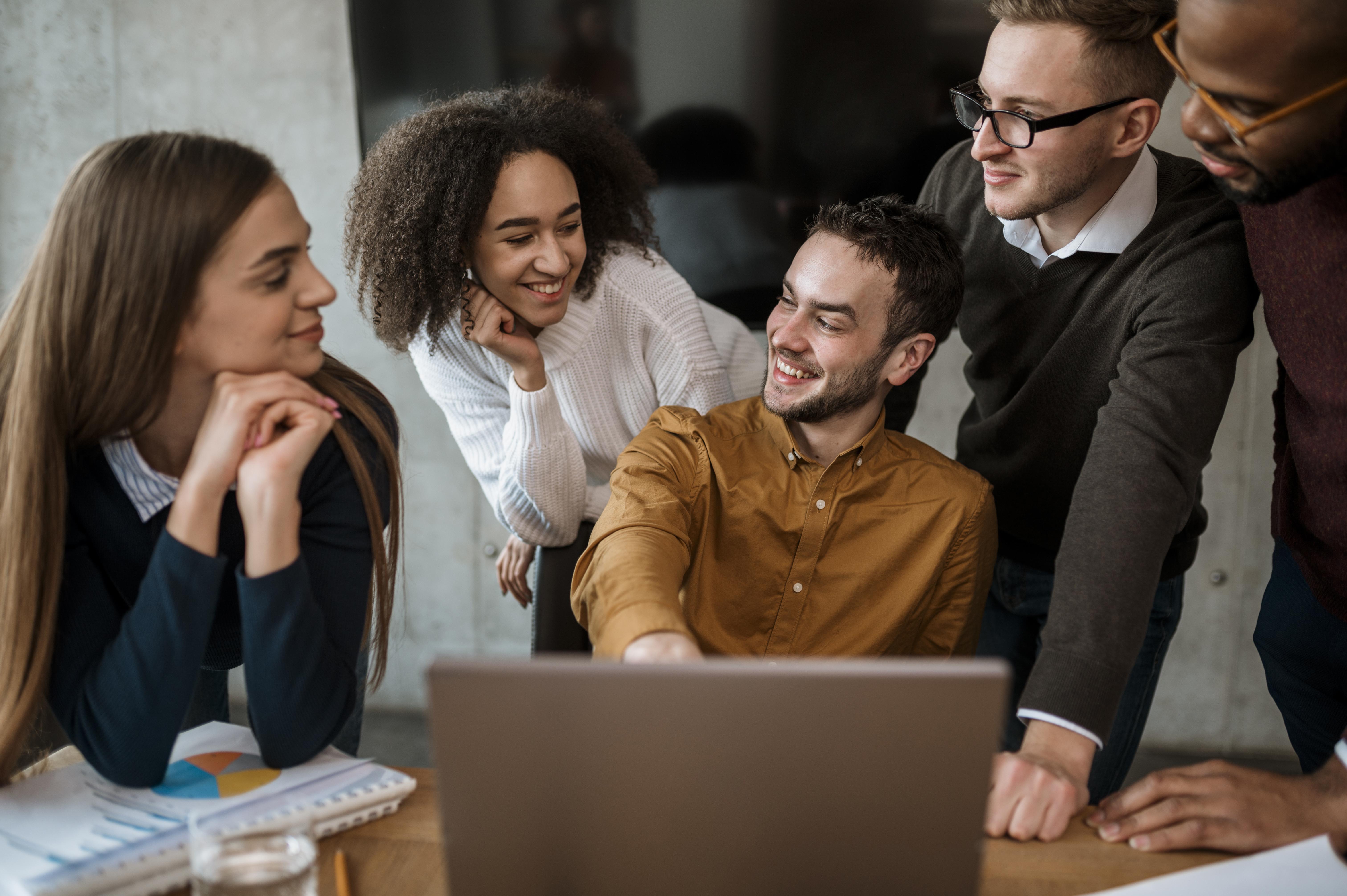 Employees gathered around a laptop. Image by Freepiks
