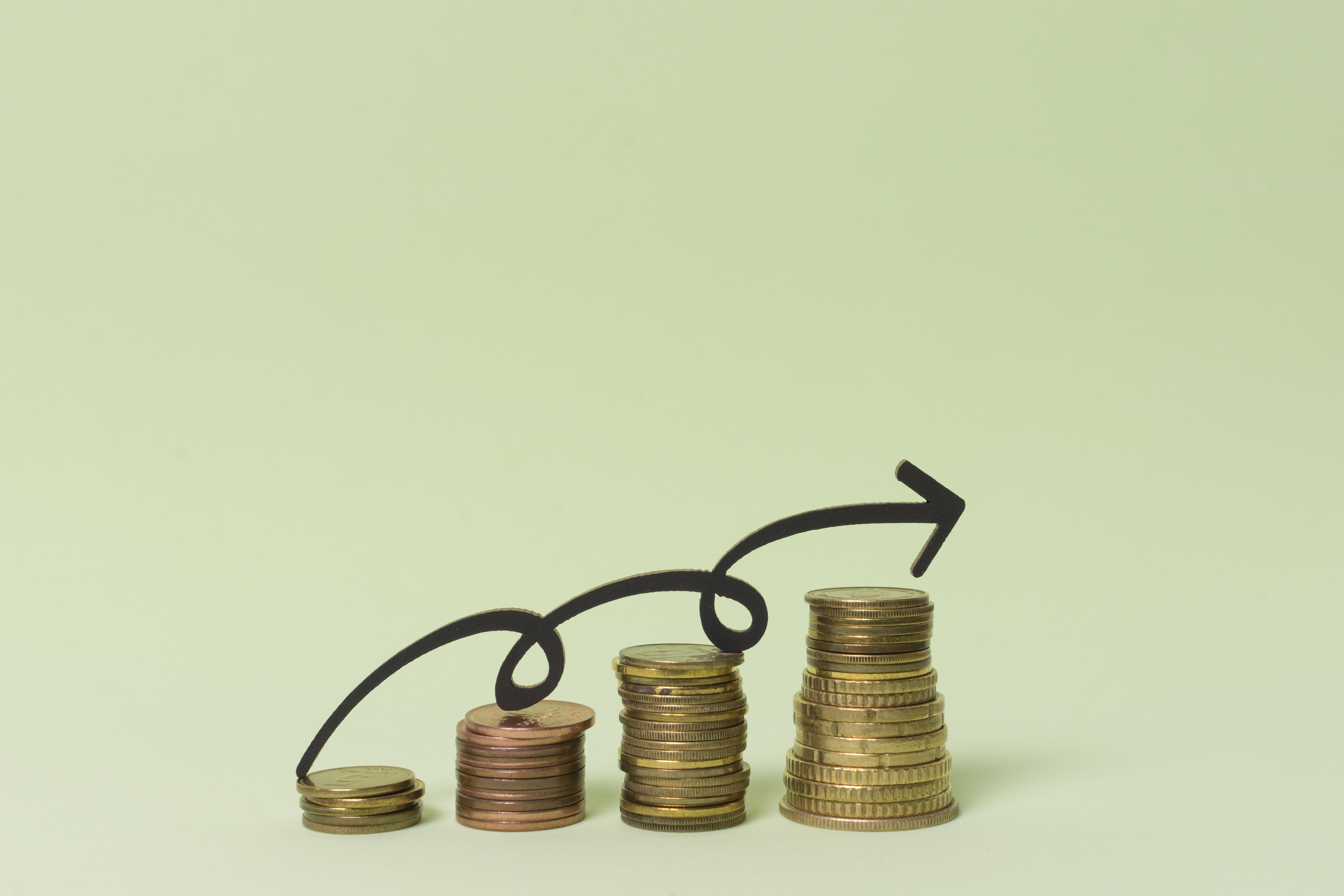 Stacks of coins growing in size with increasing arrow.