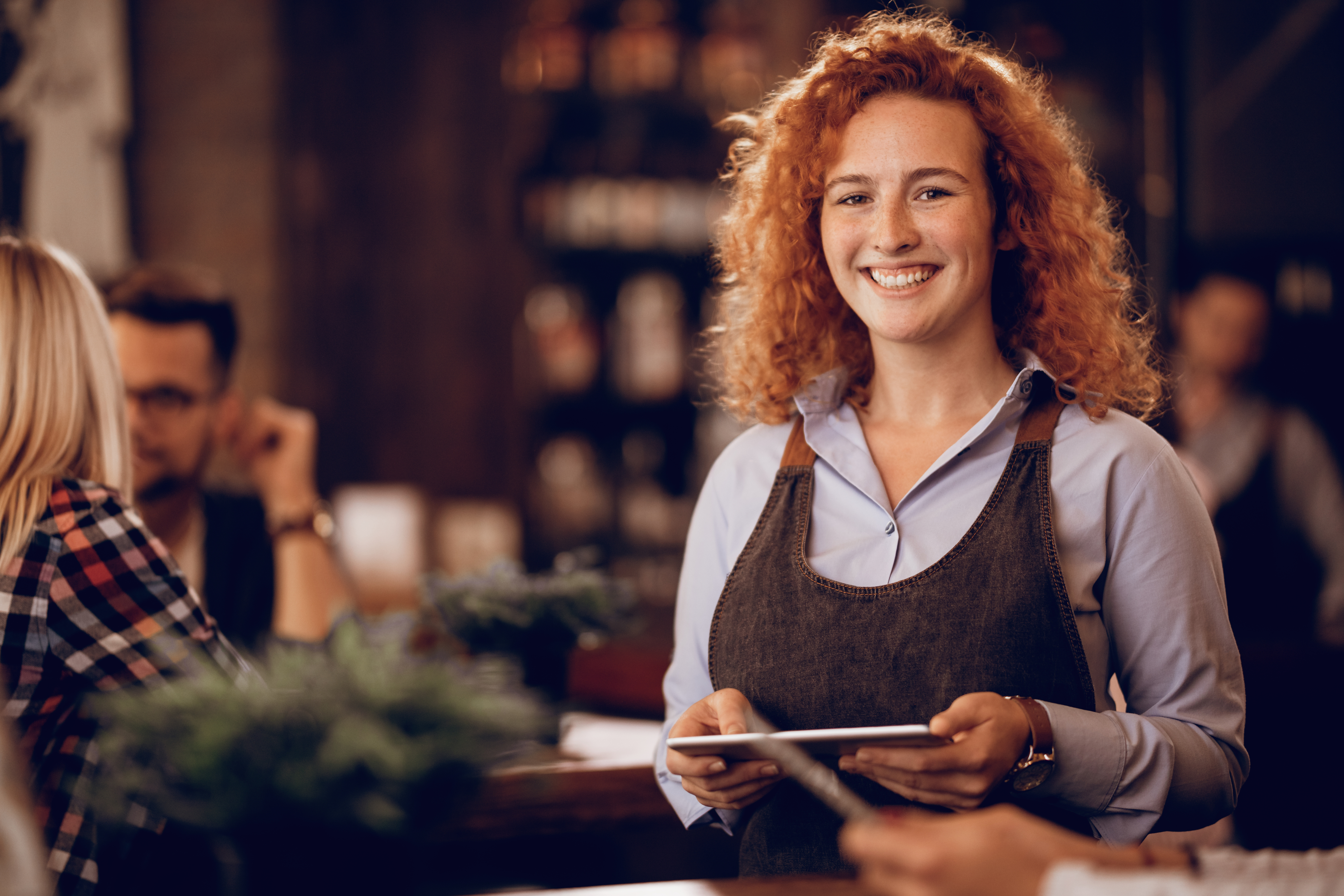 Restaurant owner with tablet smiling at camera. Image by Freepik.