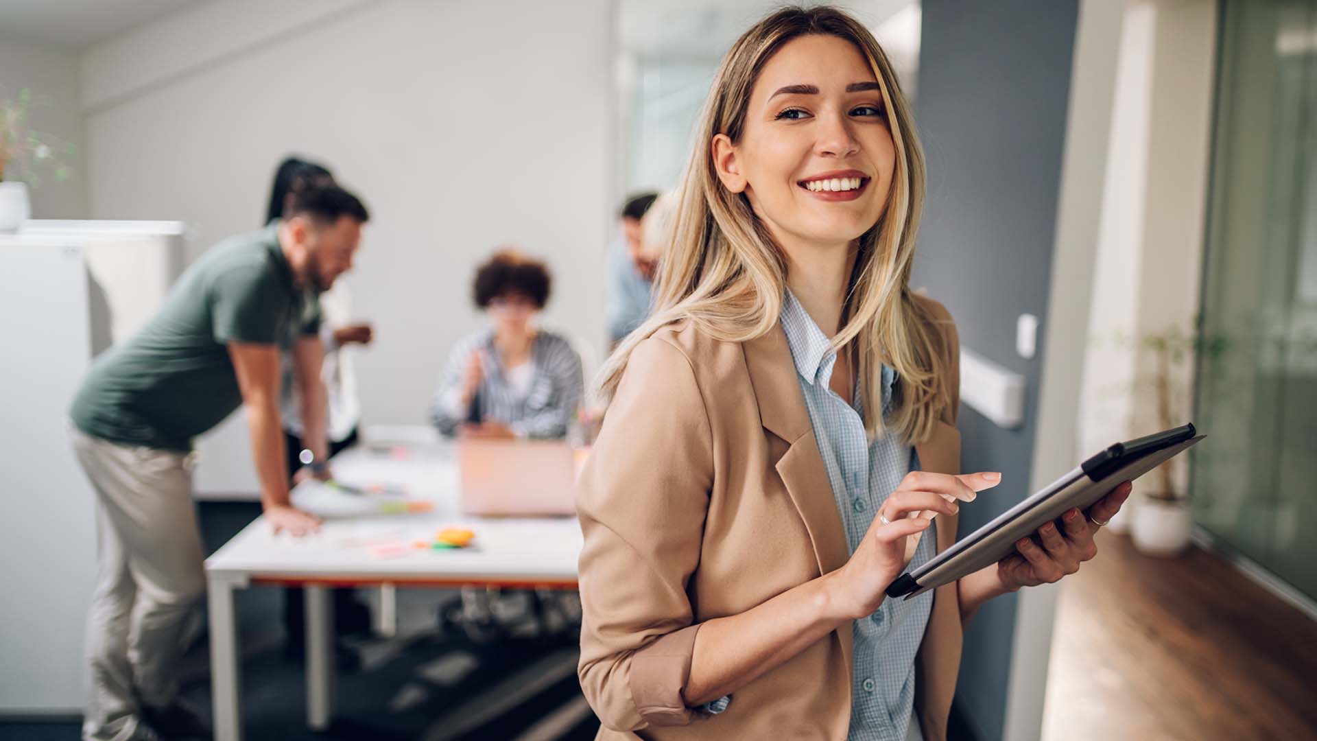 A young professional smiles while she works on a tablet.