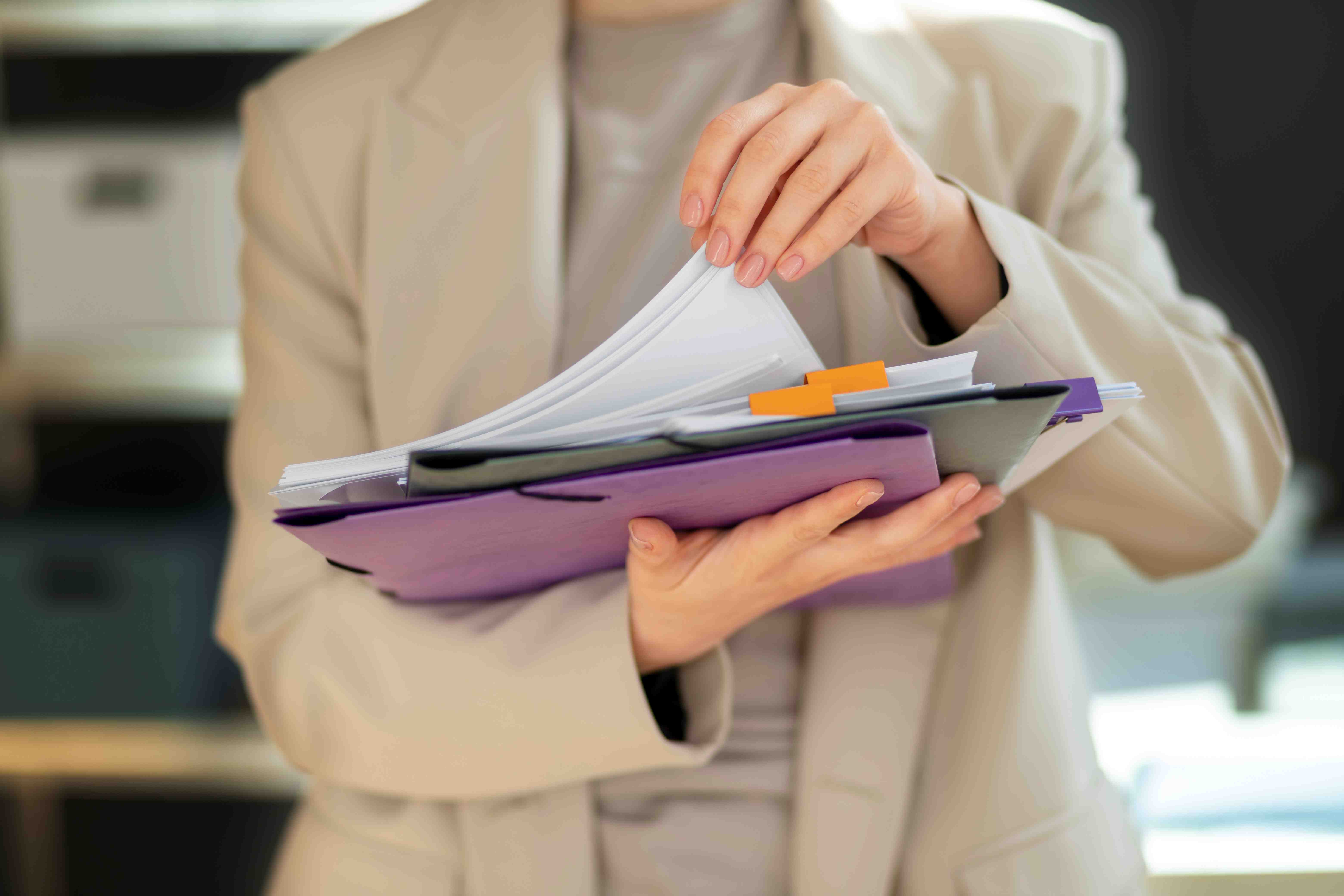 Individual holding printed sheets of paper. Image by Freepiks.
