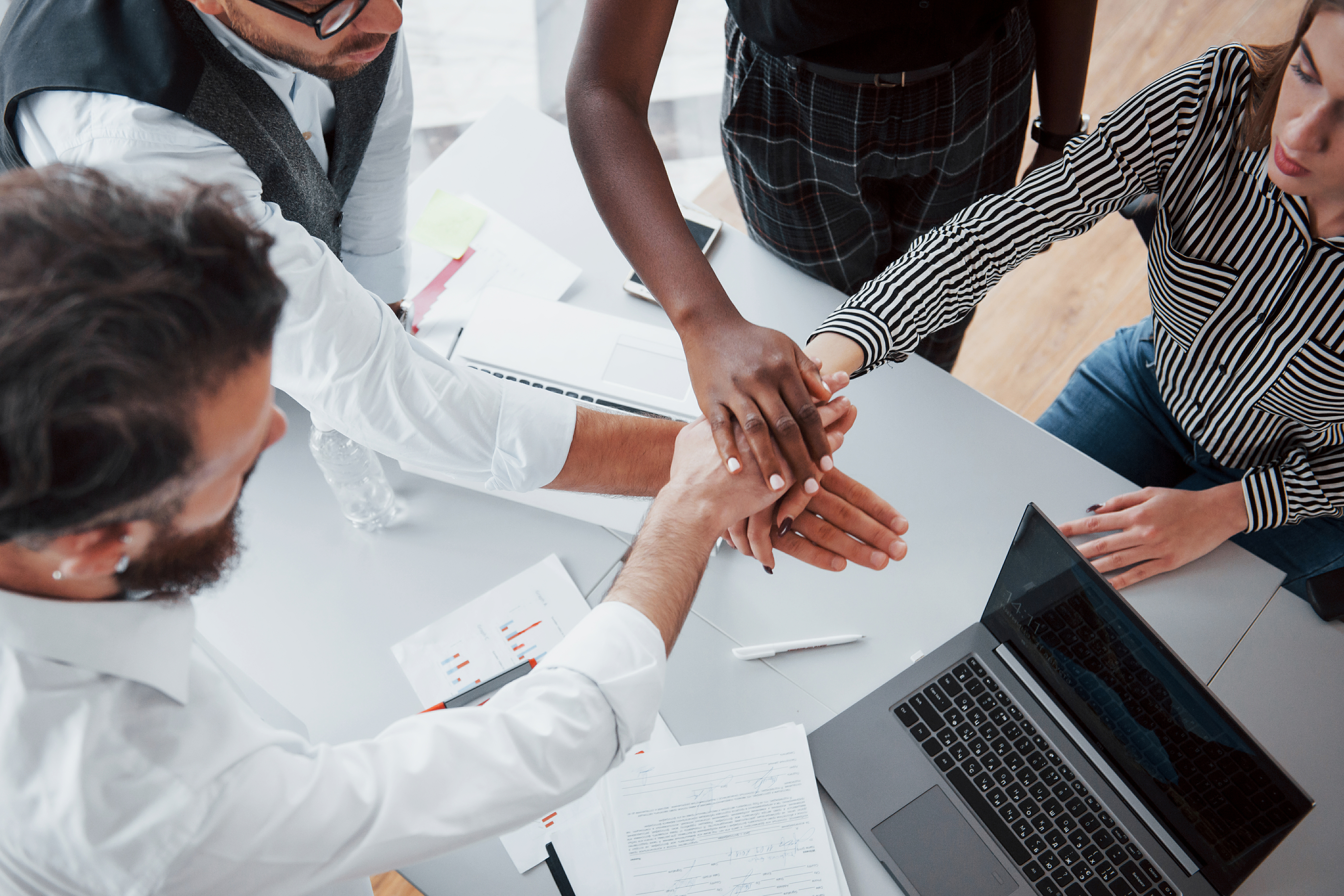 Coworkers putting their hands in the middle of the table.