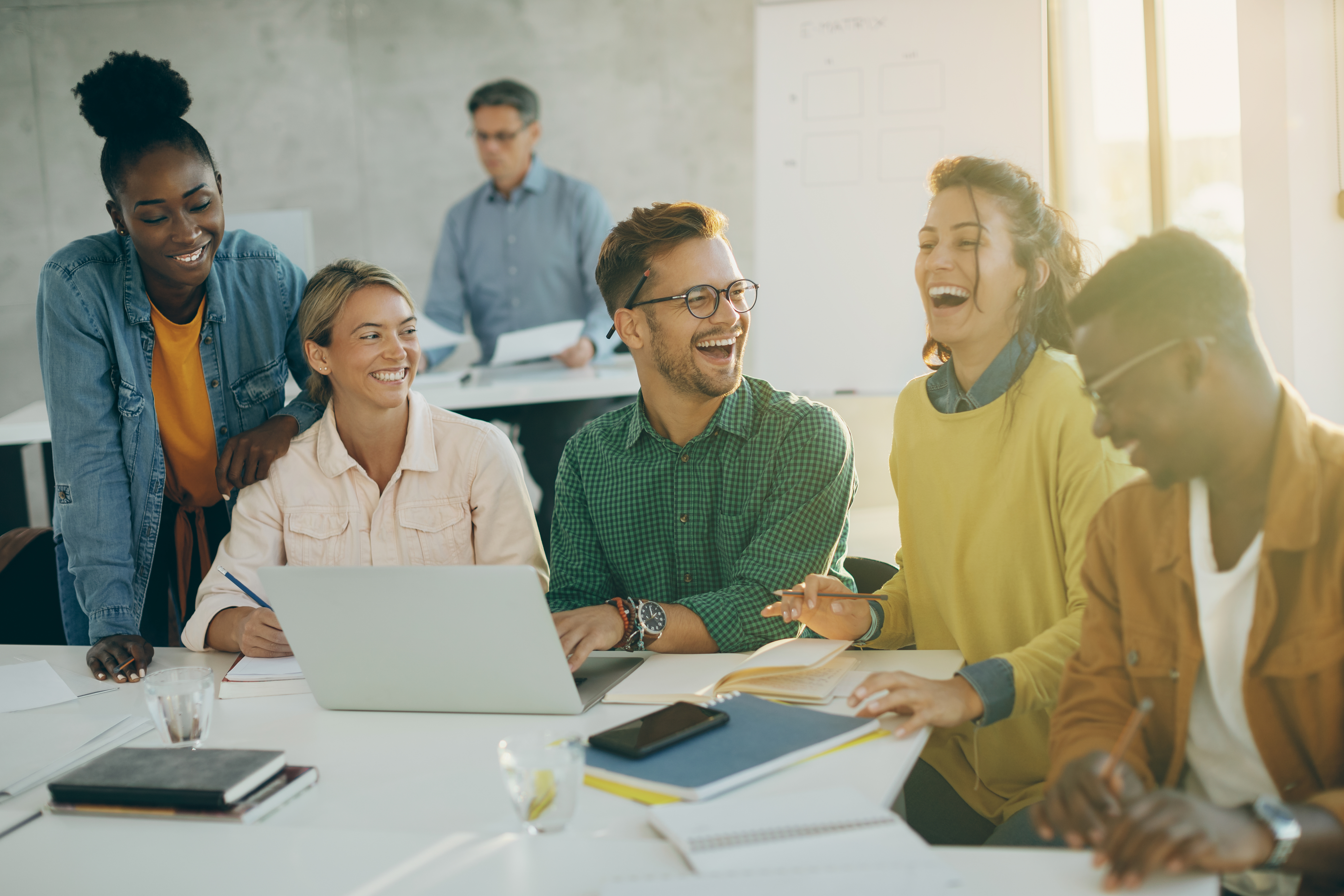 Employees gathered around a table lively discussing. Image by Freepiks